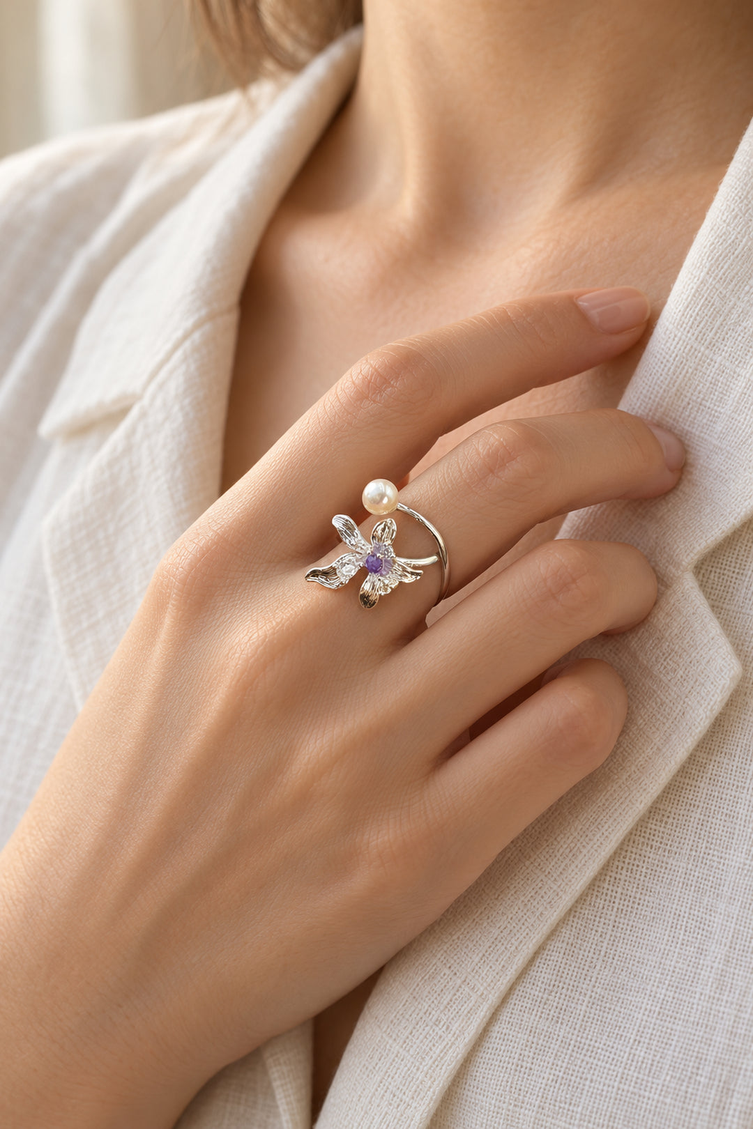 Nahaufnahme des getragenen APAERZ FIORELLA Rings mit silberfarbener Blüte und Süßwasserperle