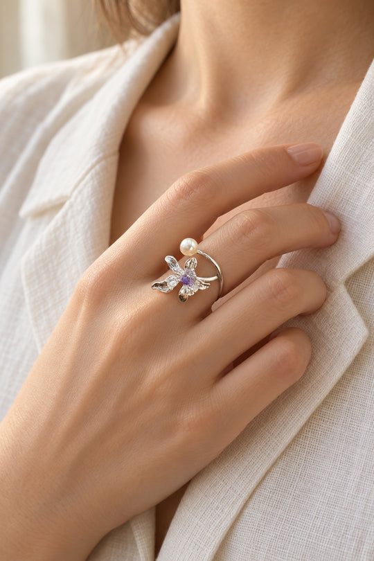 Nahaufnahme des getragenen APAERZ FIORELLA Rings mit silberfarbener Blüte und Süßwasserperle