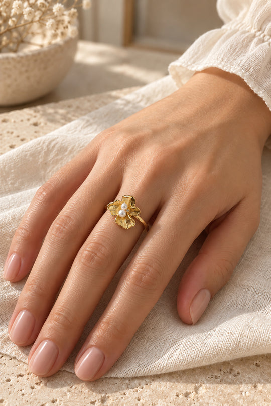 Nahaufnahme des getragenen APAERZ FLORINA Rings mit goldfarbener Blüte und Süßwasserperlen
