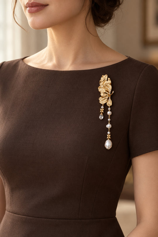 Goldfarbene APAERZ CAMELIA Blütenbrosche mit langen Perlenanhängern an einem braunen Kleid